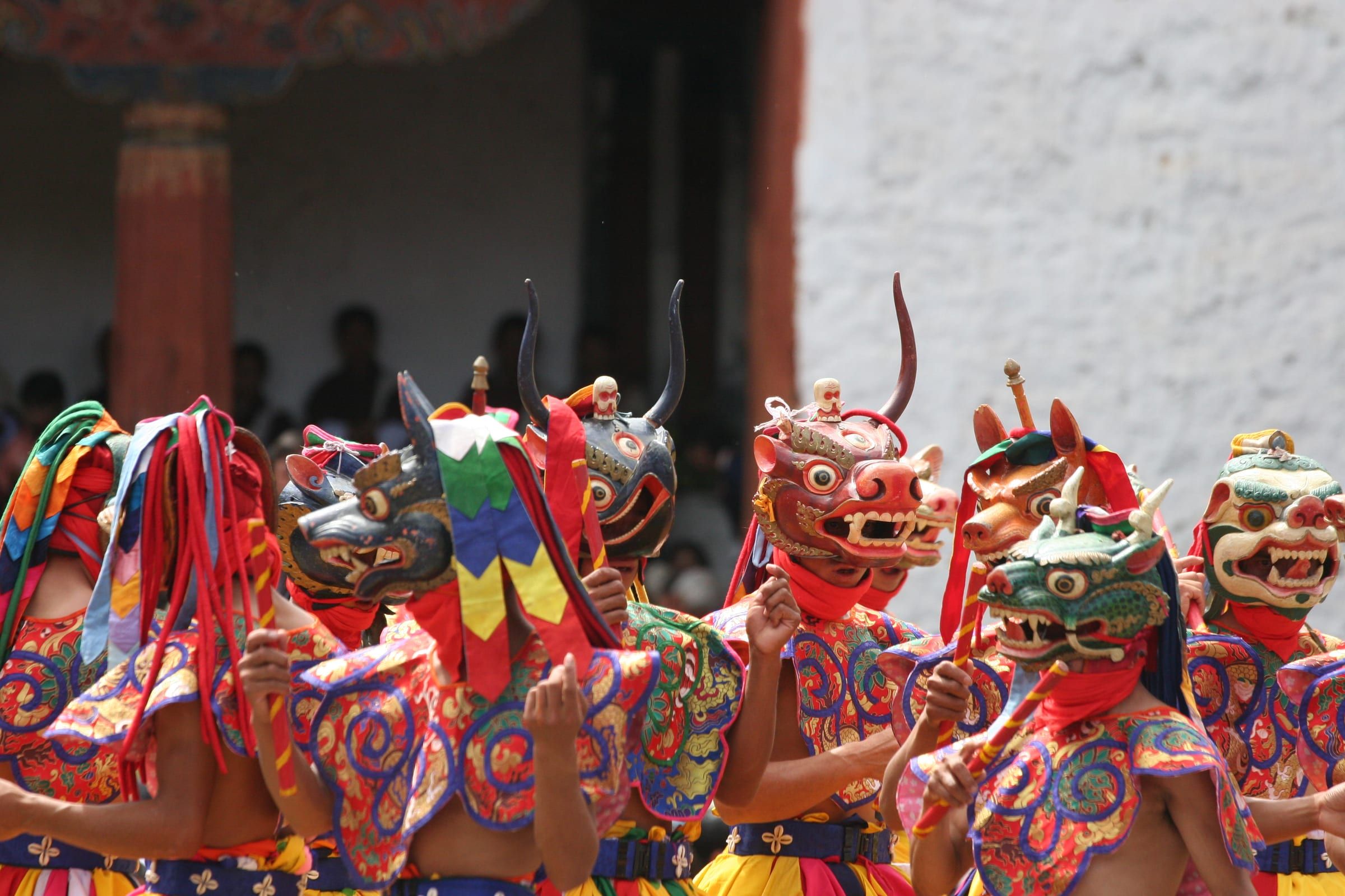 Dancers in animal and wrathful deity masks and bright brocade robes.